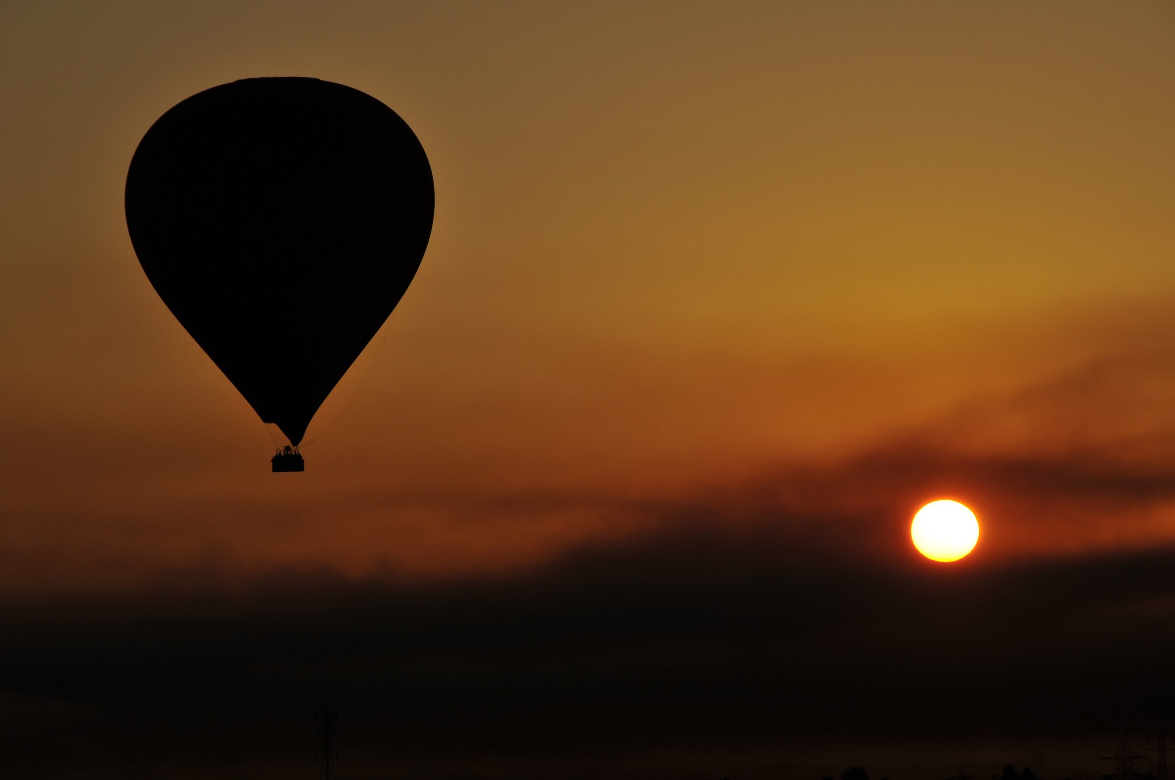 A hot-air balloon drifting over the Theban West Bank at sunrise